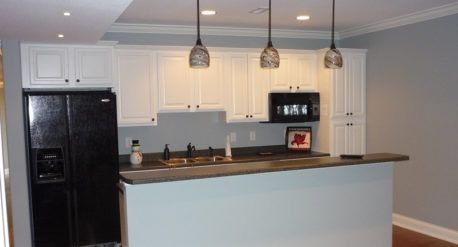 Modern kitchen with black appliances, white cabinets, pendant lights, and a breakfast bar