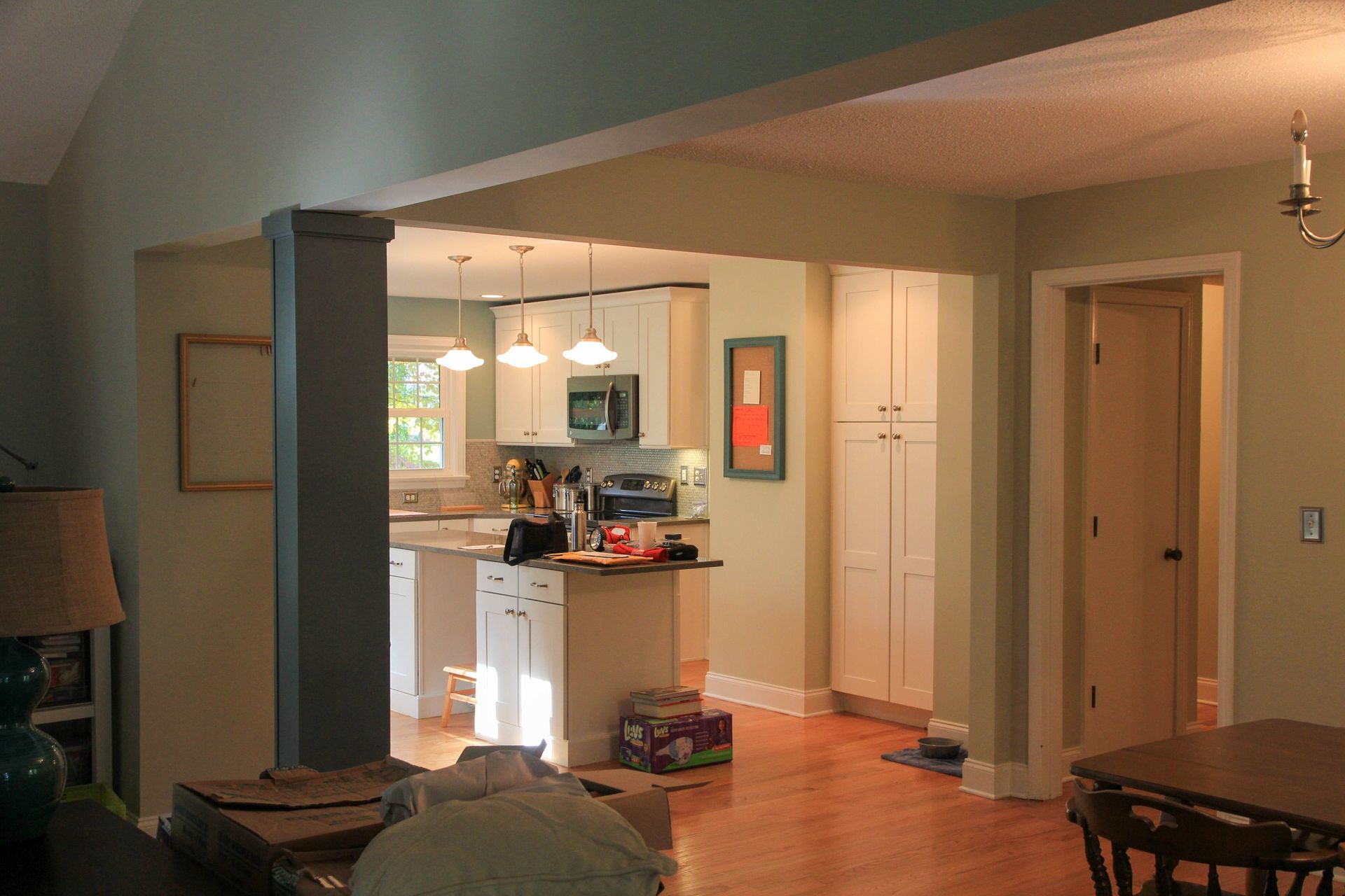 Open-plan kitchen and dining area with wood floors, white cabinets, and warm lighting