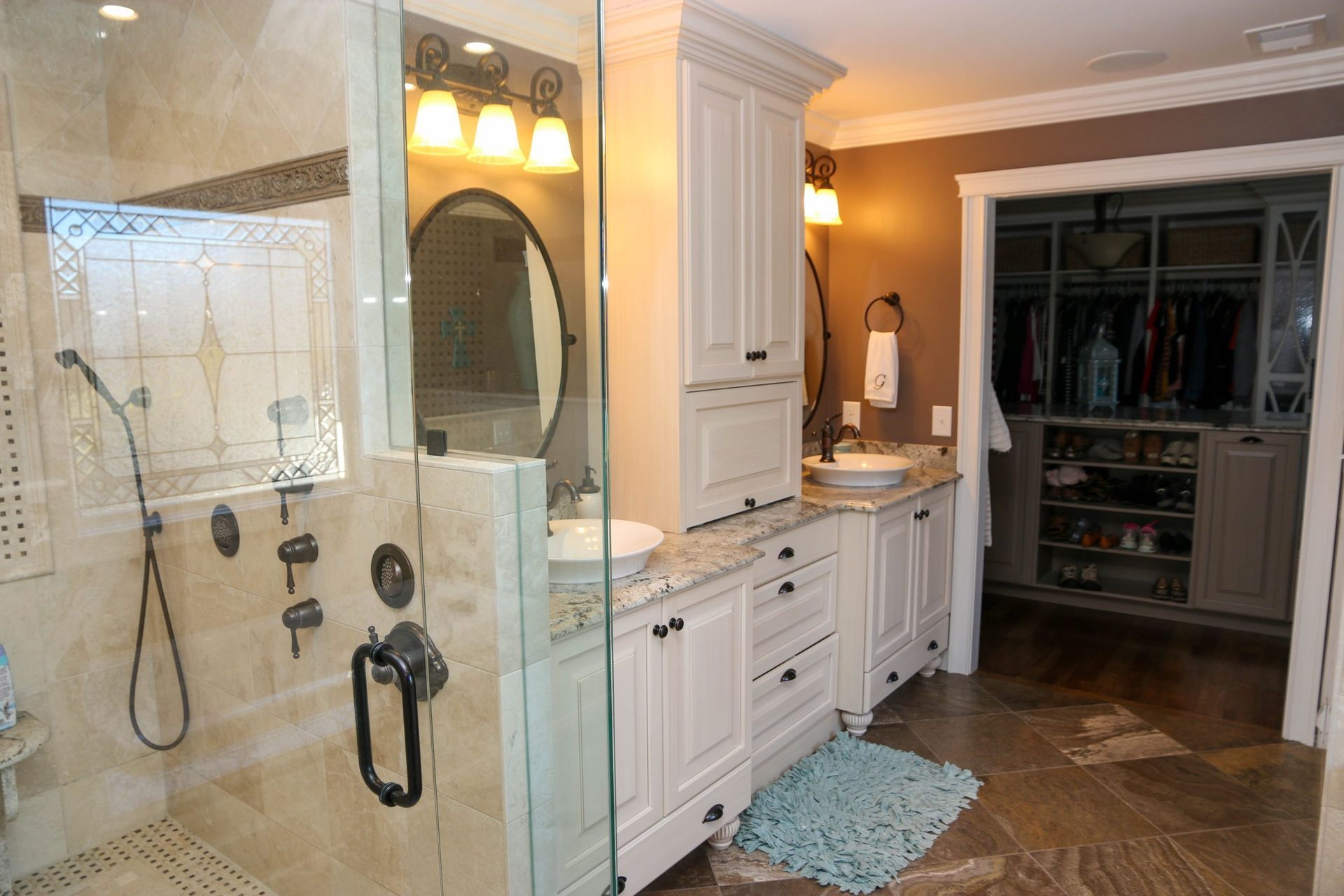 Luxurious bathroom with glass shower, white vanity, and open walk-in closet beyond