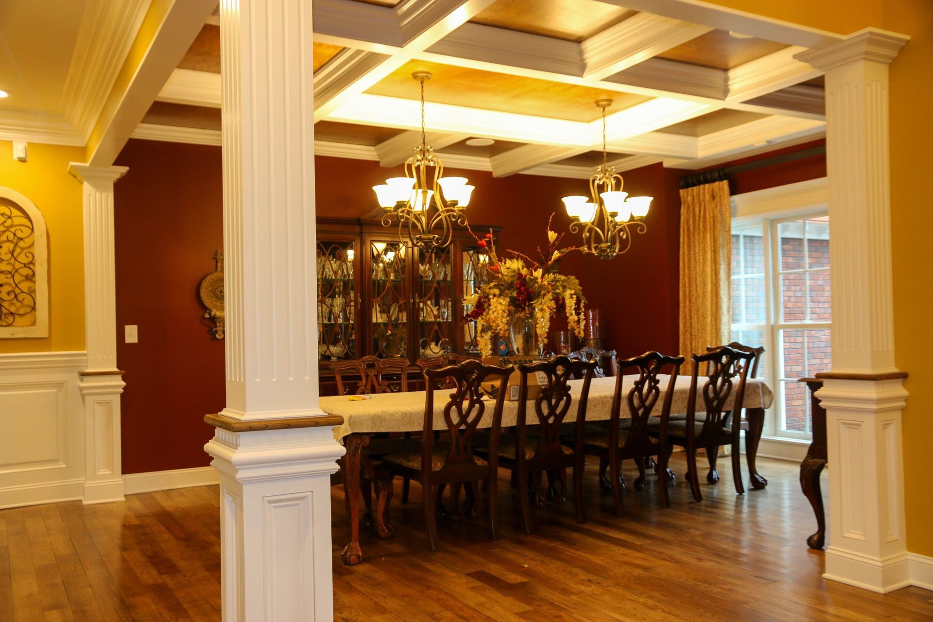 Elegant dining room with long table, dark chairs, chandelier, and warm wood floors