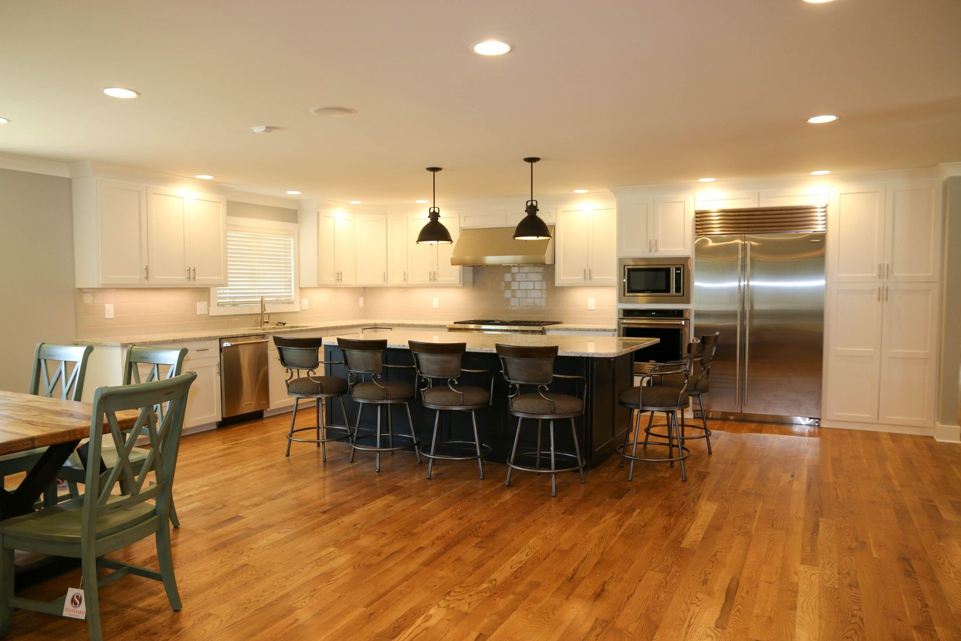 Modern kitchen with island seating, stainless steel appliances, and hardwood floors