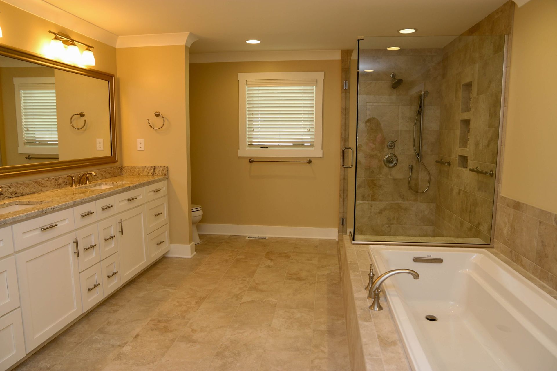 Spacious beige bathroom with double vanity, large mirror, walk-in shower, and jetted tub.