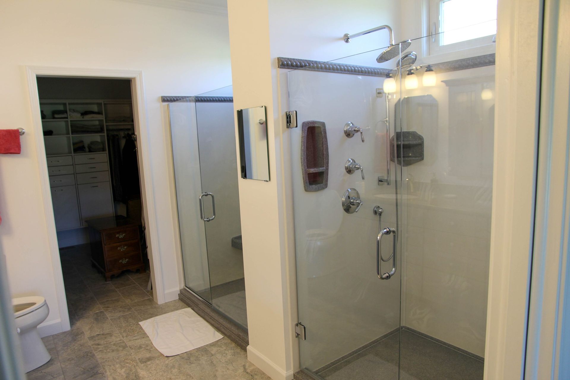 Bathroom with a glass-enclosed shower, tiled floor, and an open closet doorway.