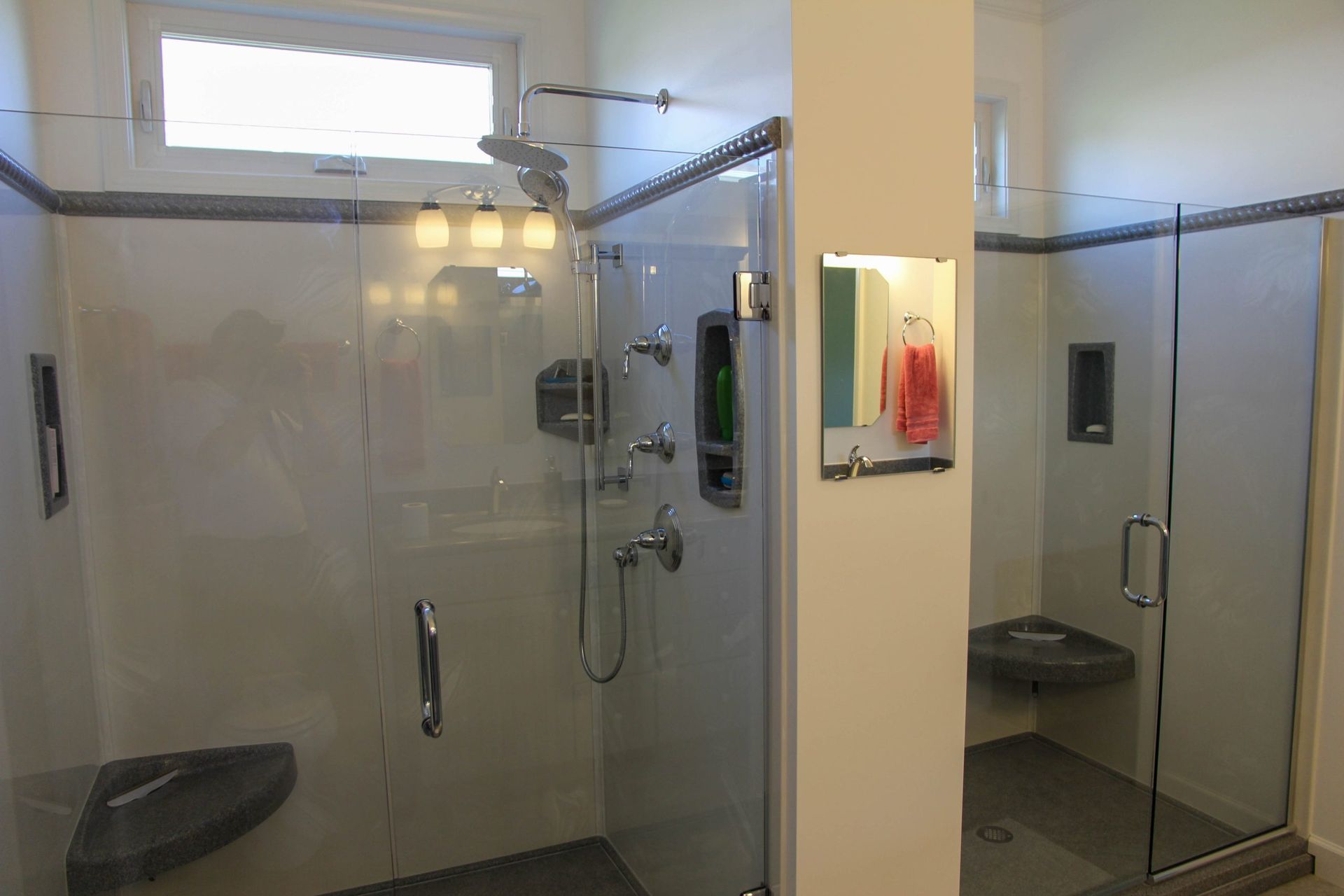 Modern shower room with two glass-enclosed showers, beige walls, and a red soap dispenser on the center column