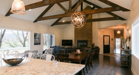 Open-concept kitchen and dining room with vaulted wood beams and dark hardwood floors