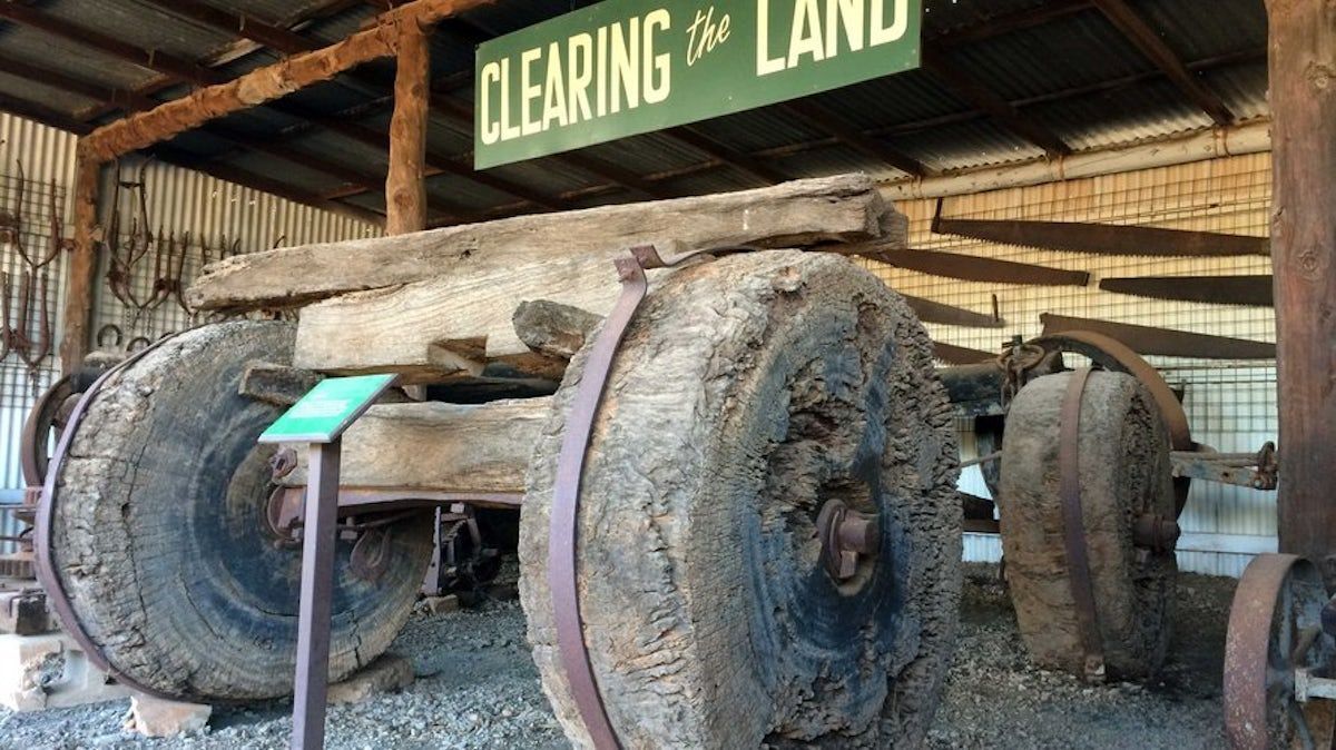 Old steam engine under a shed, with a sign reading “Clearing the Land” above it.