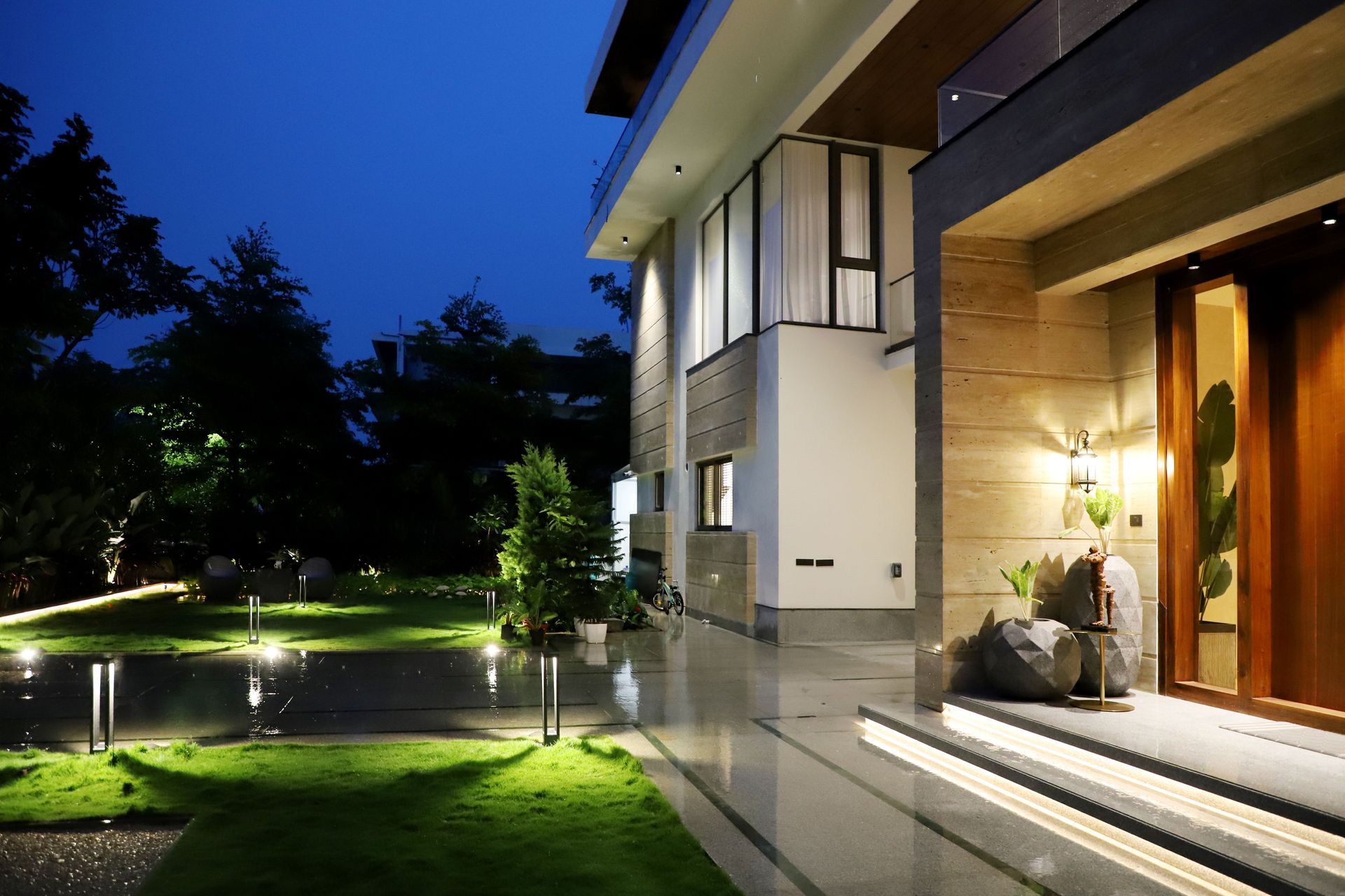 Modern house at dusk with lit garden path and warm light from the doorway