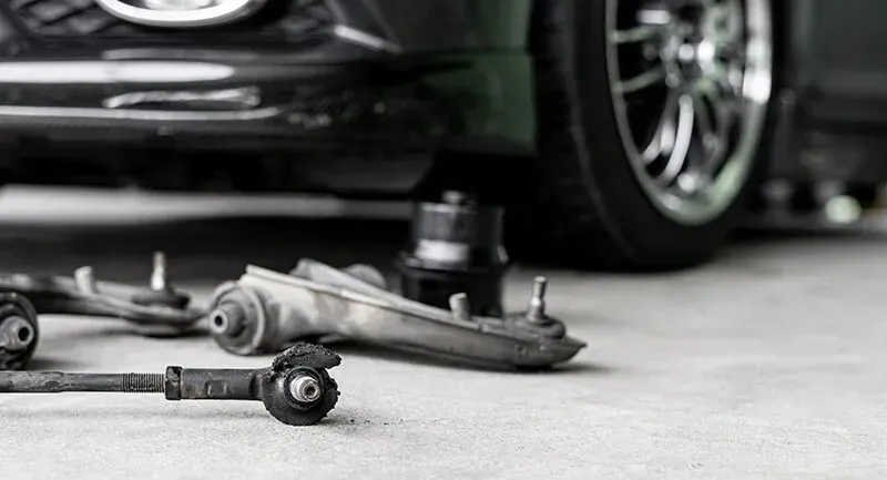 Car suspension parts scattered on ground beneath a vehicle's tire | Calgary Auto and Alignment