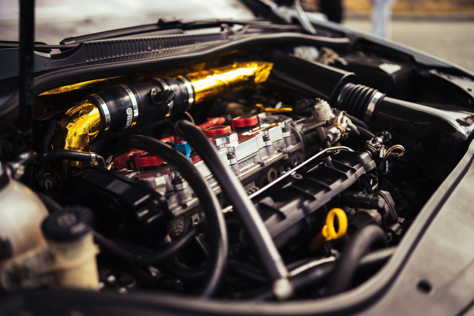 Close-up of a car engine bay with polished metal intake pipes and hoses