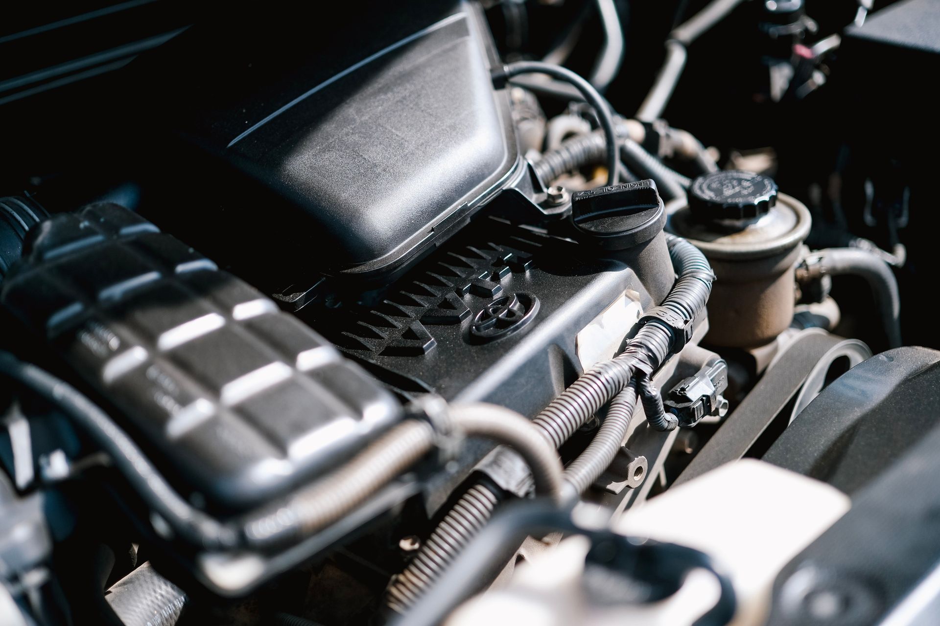 Close-up of a car engine bay with black components and visible hoses.