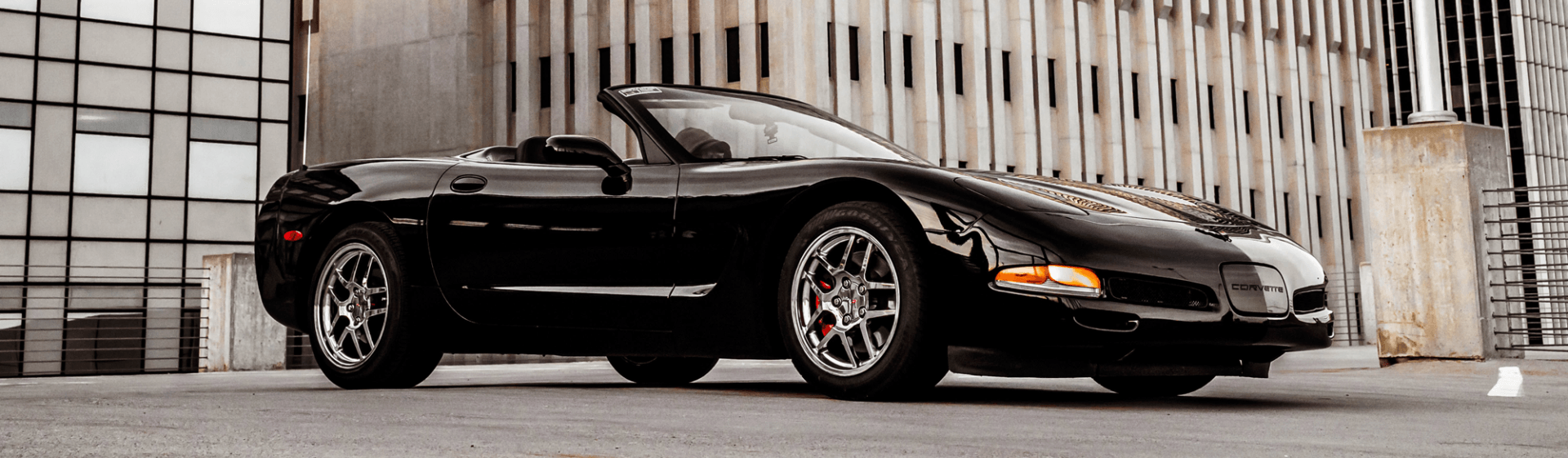 A black convertible sports car is parked in front of a building.