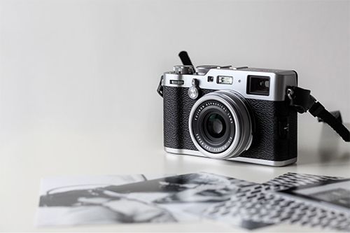 A black and silver camera is sitting on top of a white table.