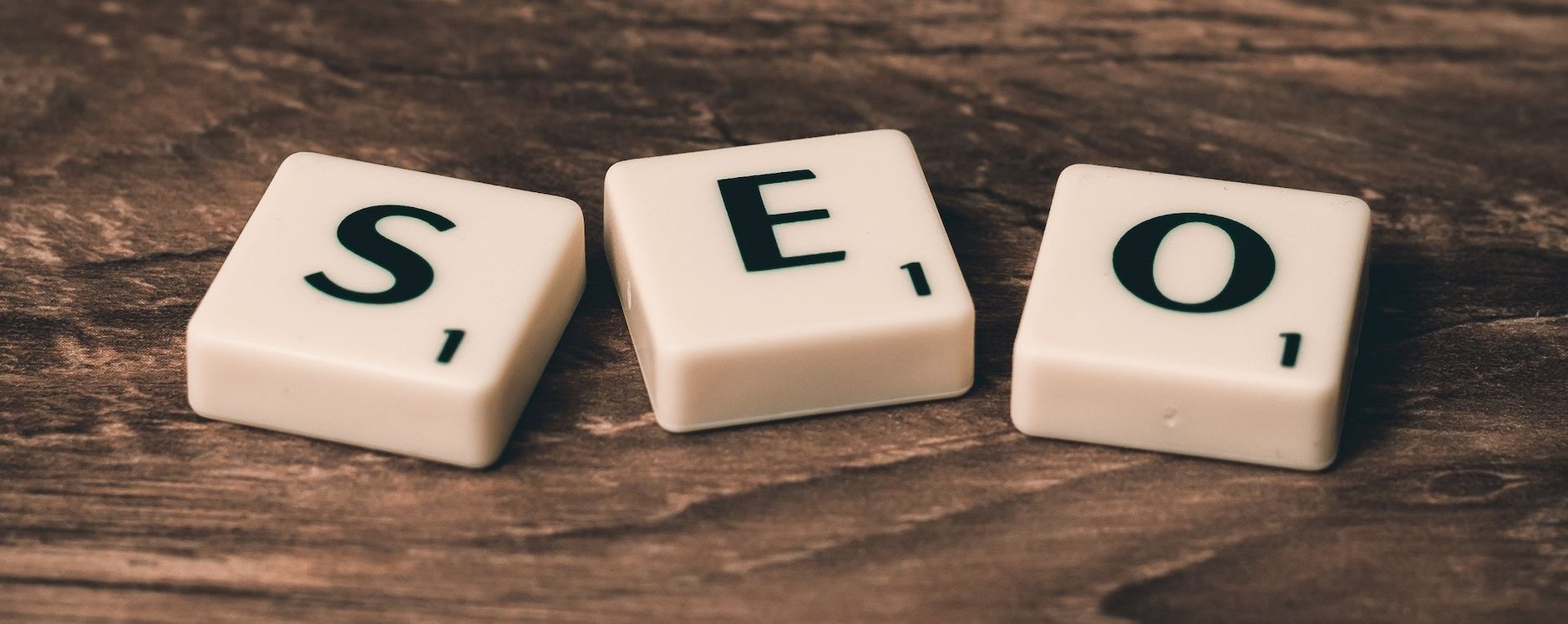 The word seo is written on scrabble tiles on a wooden table.