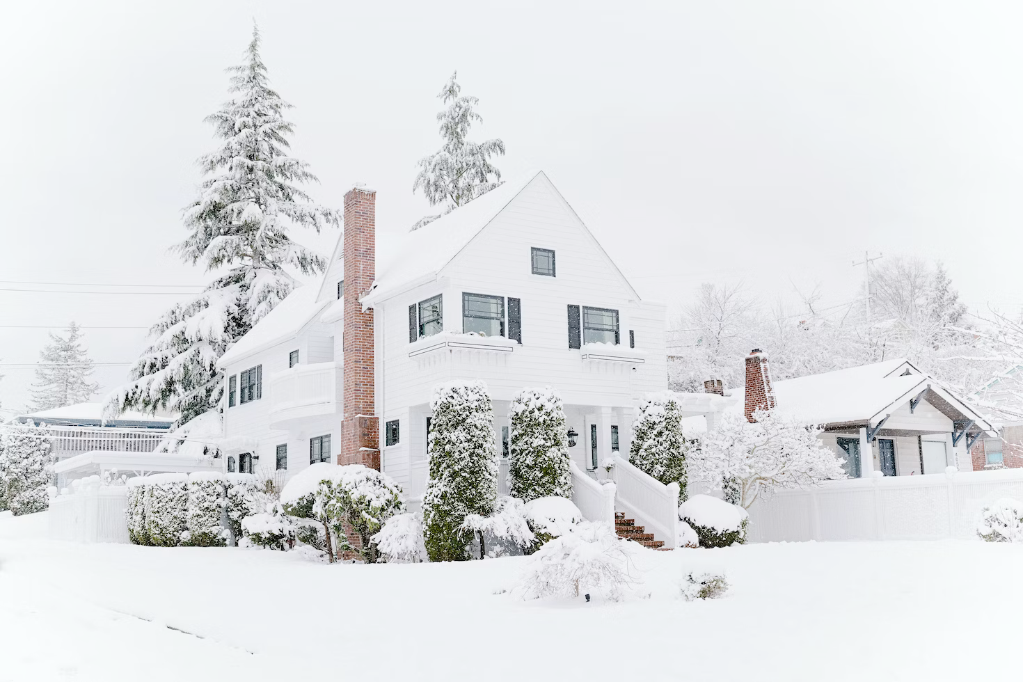 A large white house is covered in snow.