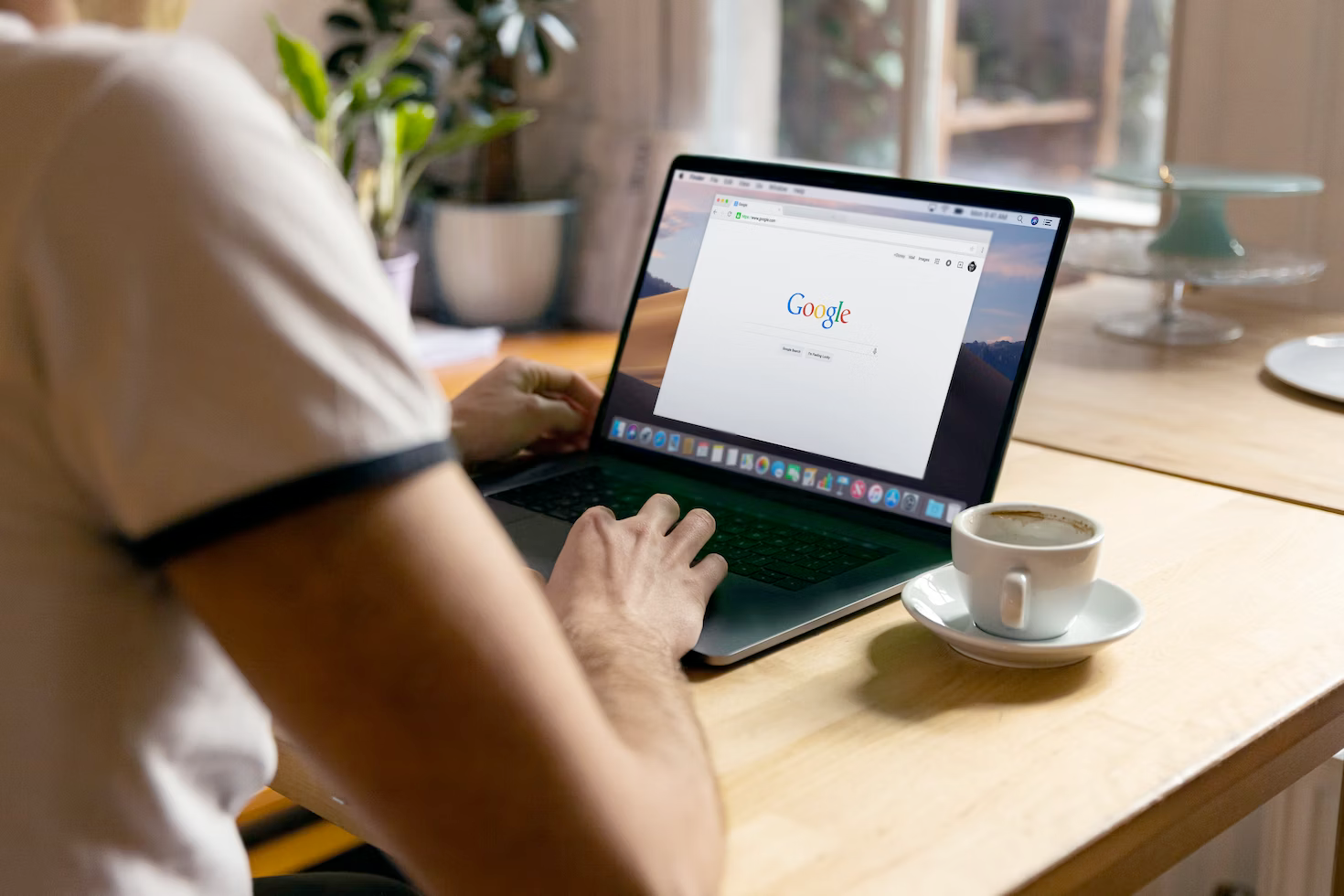 A man is sitting at a table using a laptop computer.