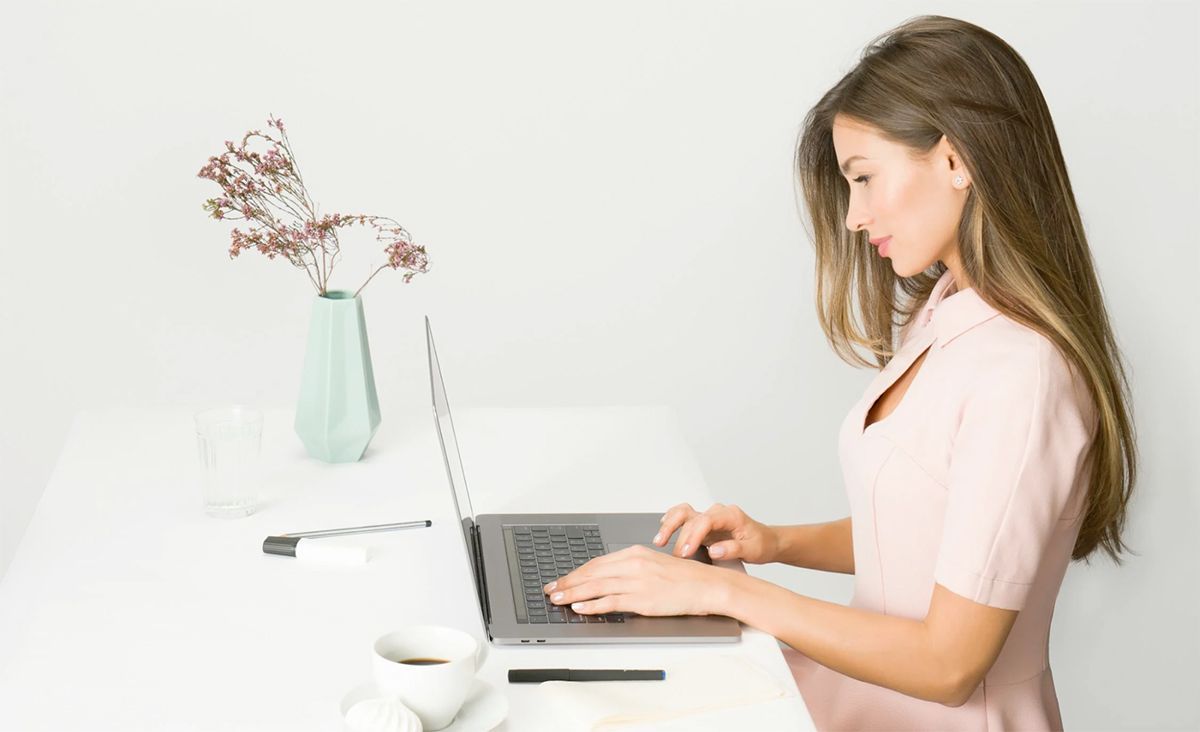A woman is sitting at a desk using a laptop computer.