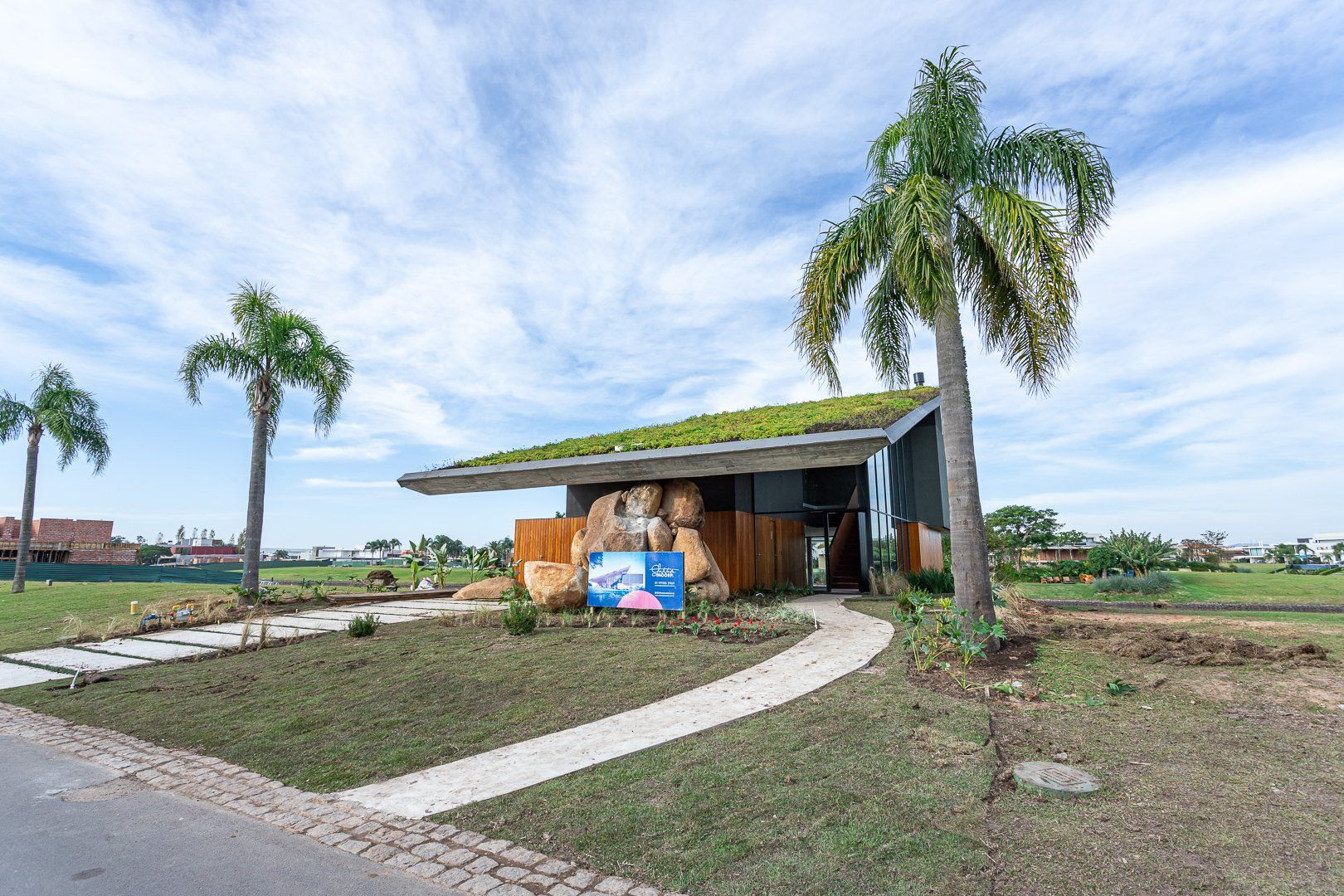 Uma casa com telhado verde e palmeiras na frente.