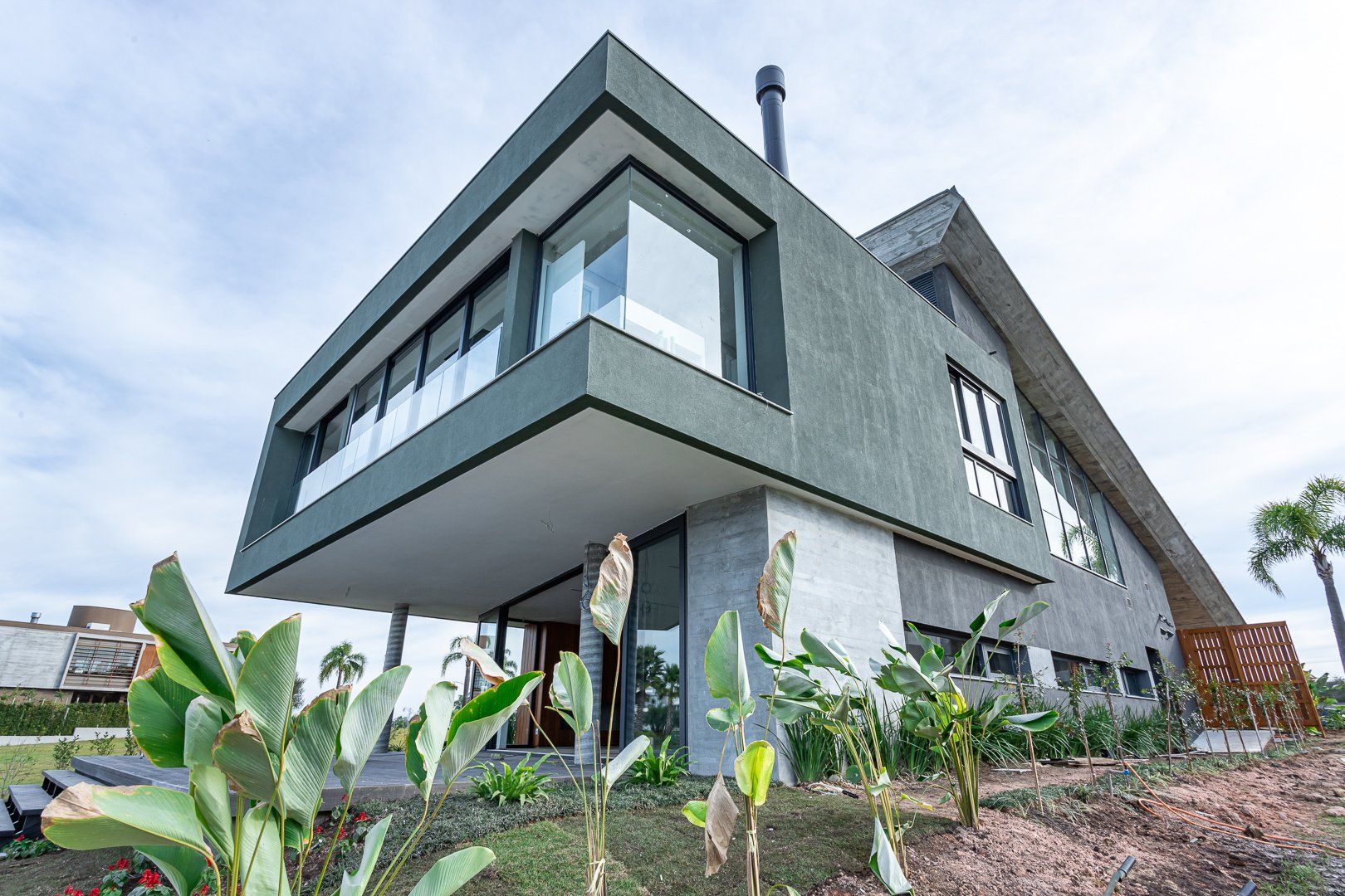 Uma grande casa moderna com muitas janelas fica no topo de uma colina.
