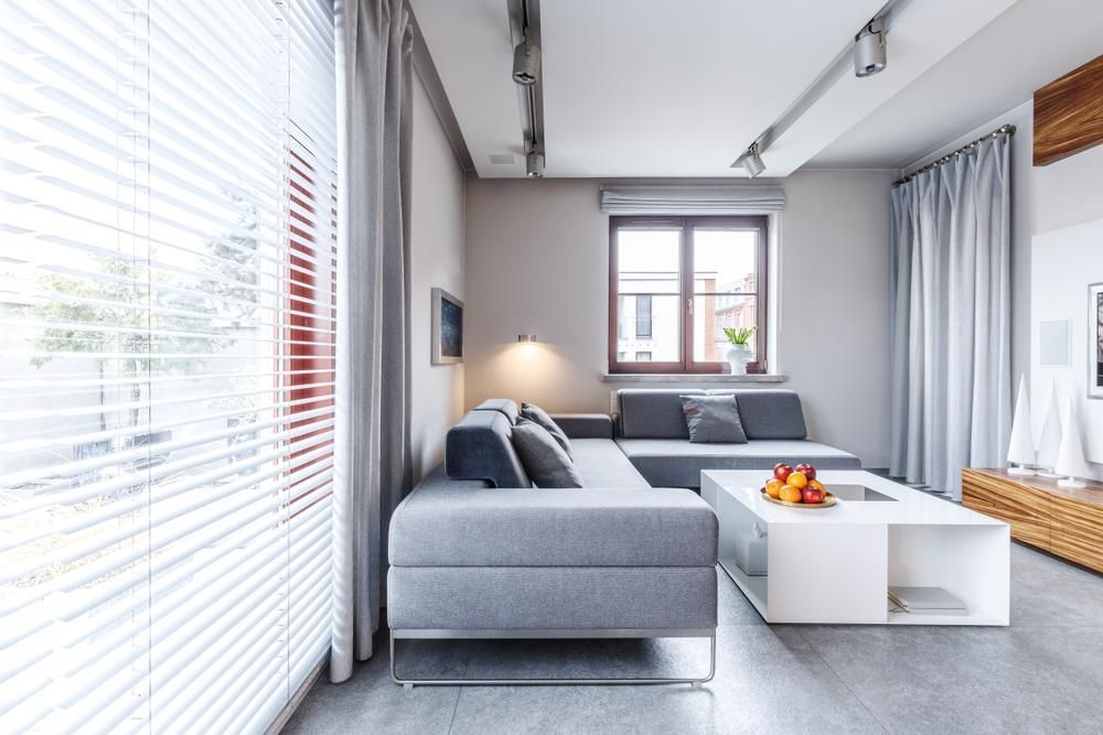 A House With White PVC Plantation Shutters Next To A Grey Couch— Outdoor Blinds In Berkeley Vale, NSW