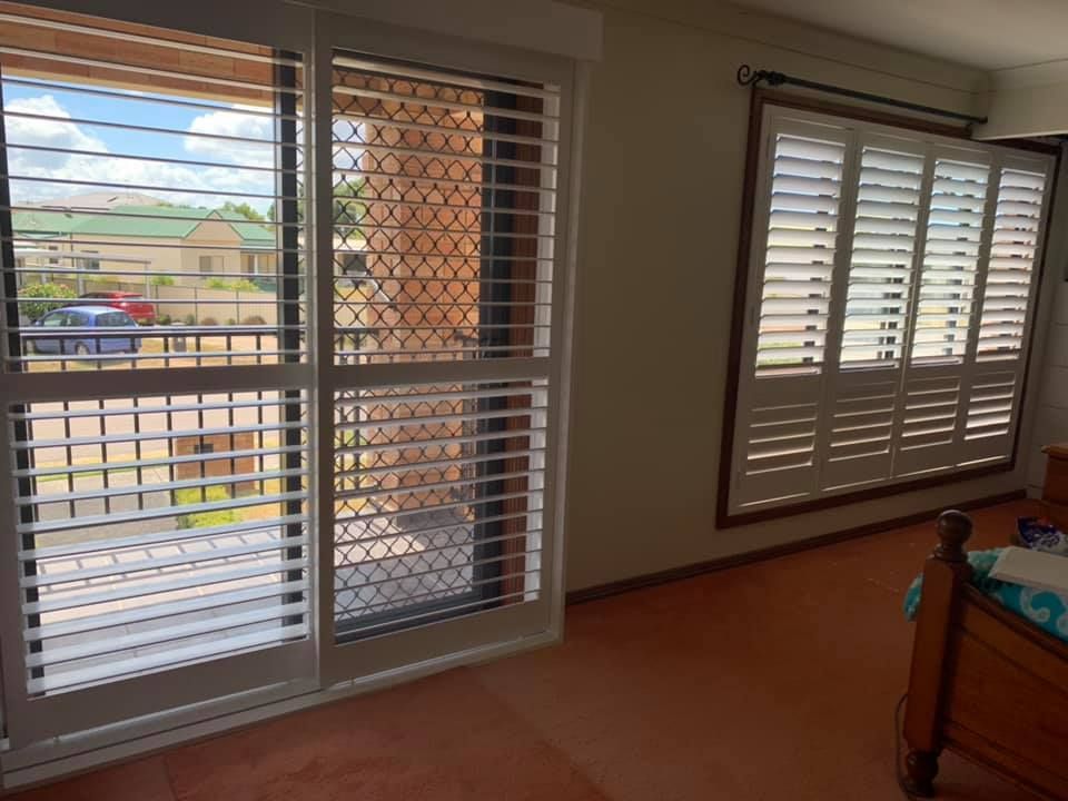 A Bedroom With Sliding Glass Doors And Shutters On The Windows — Outdoor Blinds In Berkeley Vale, NSW