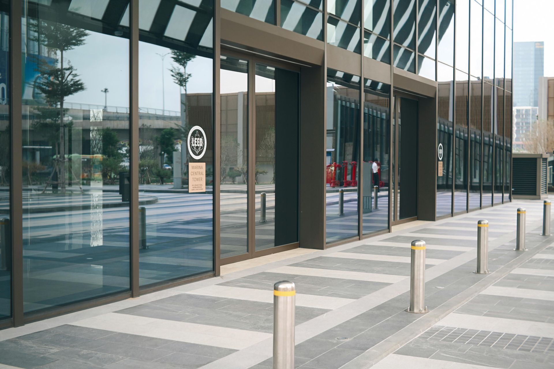 Modern glass building entrance with bollards and striped pavement outside