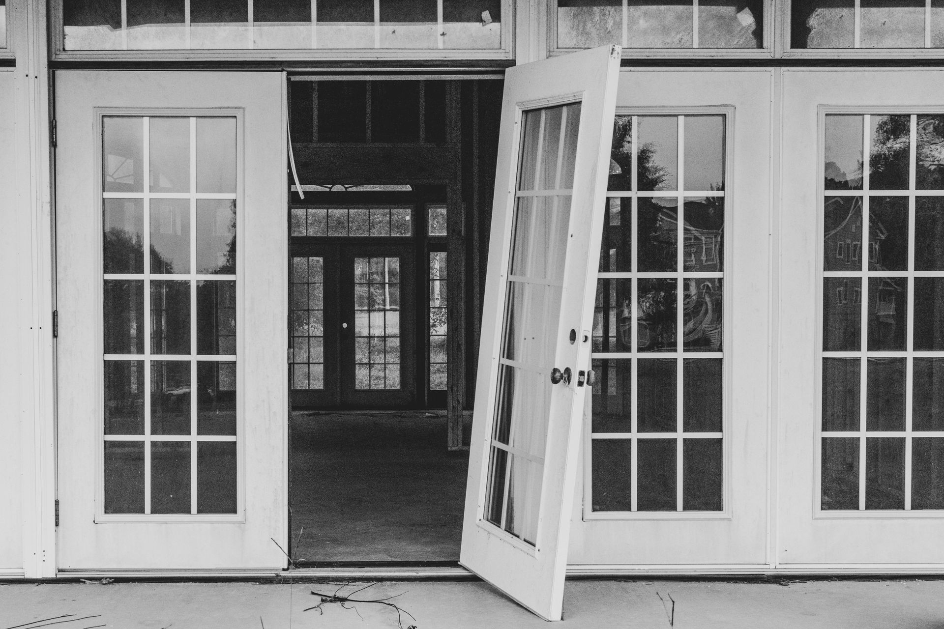 Open double doors leading into a building corridor, with glass side panels and a monochrome facade.