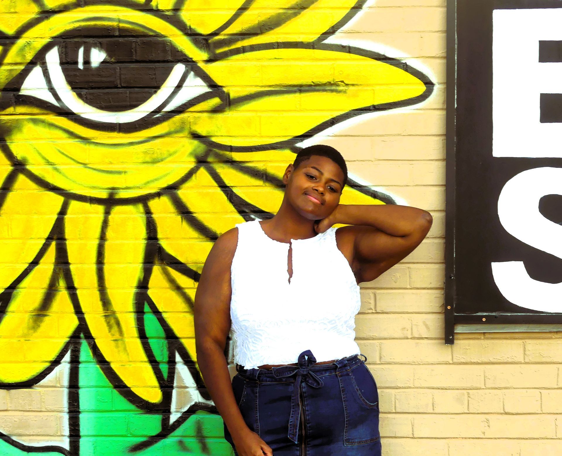 A woman is standing in front of a mural of a sunflower and an eye