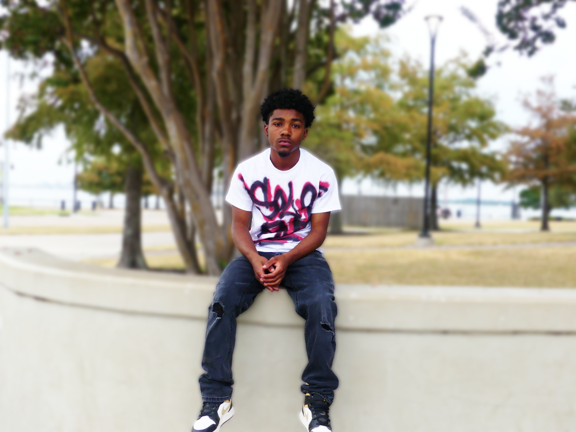 A young man is sitting on a wall wearing a t-shirt that says solo