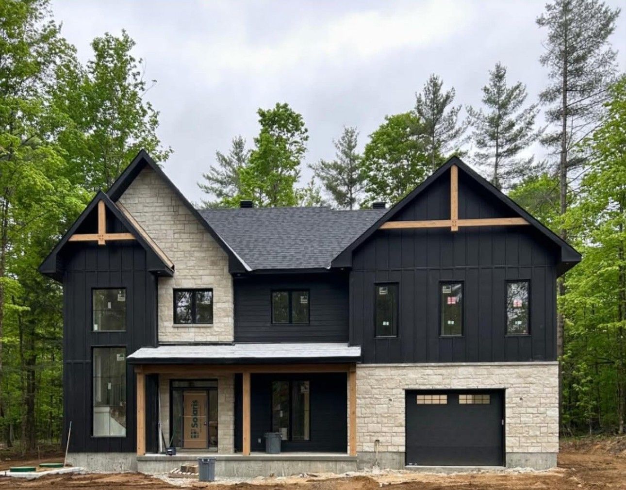 A large black and white house is being built in the middle of a forest.