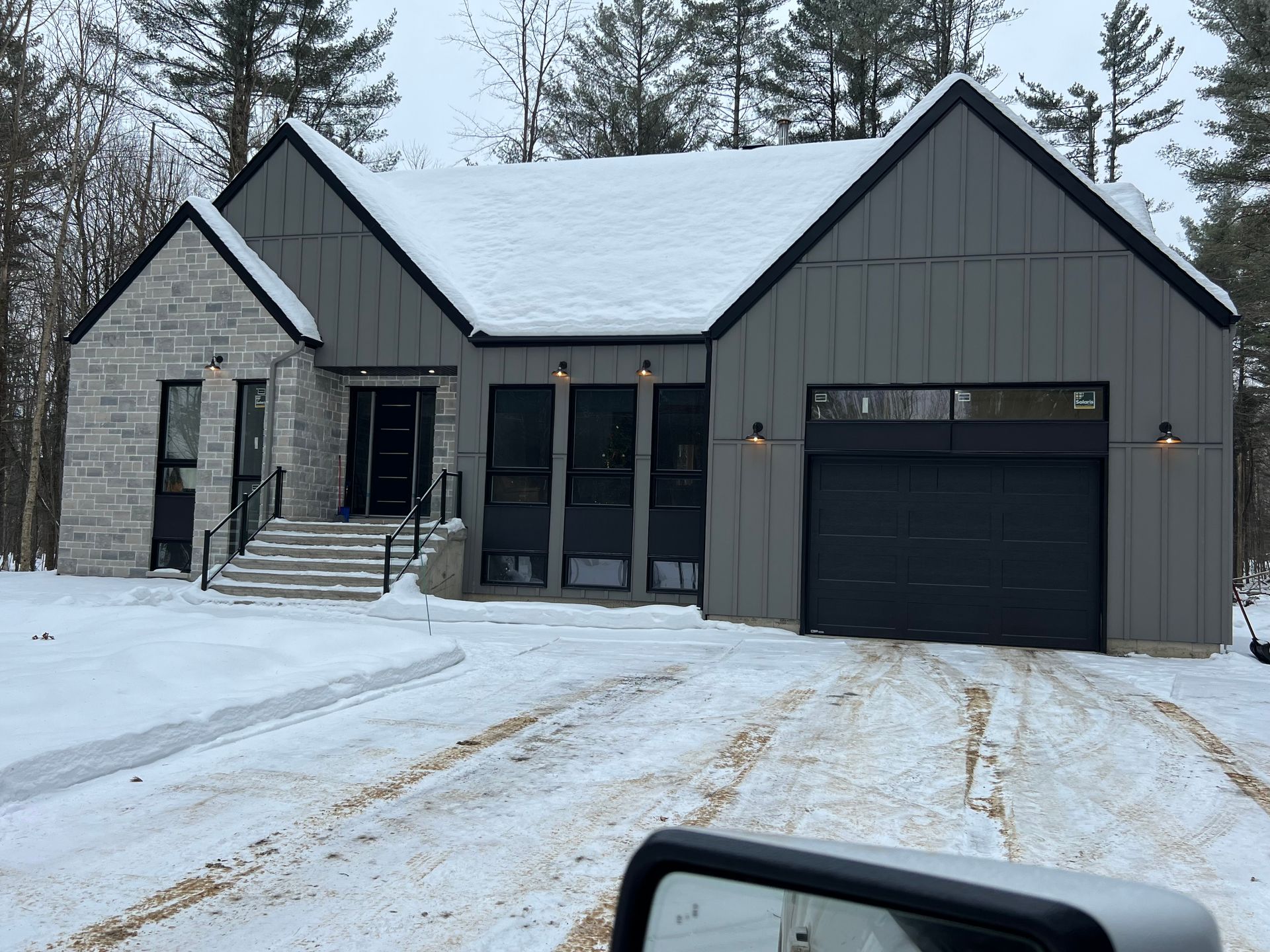 A car is parked in front of a house that is covered in snow.