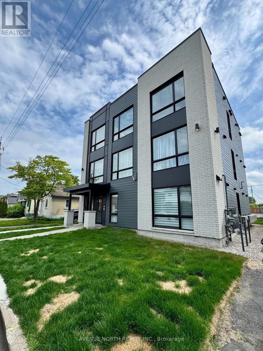 A large apartment building with a lot of windows and a lot of grass in front of it.