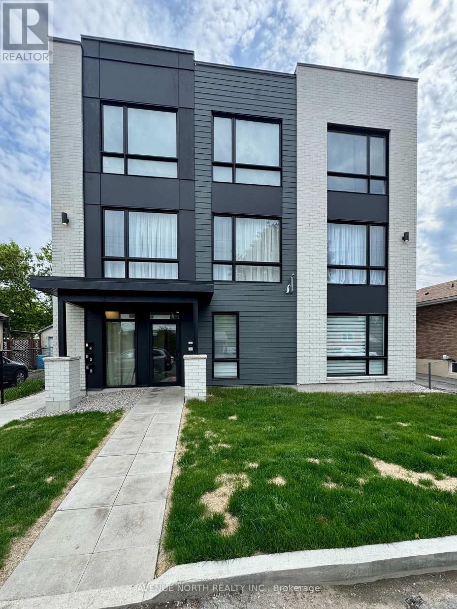 A large apartment building with a lot of windows and a lush green lawn in front of it.