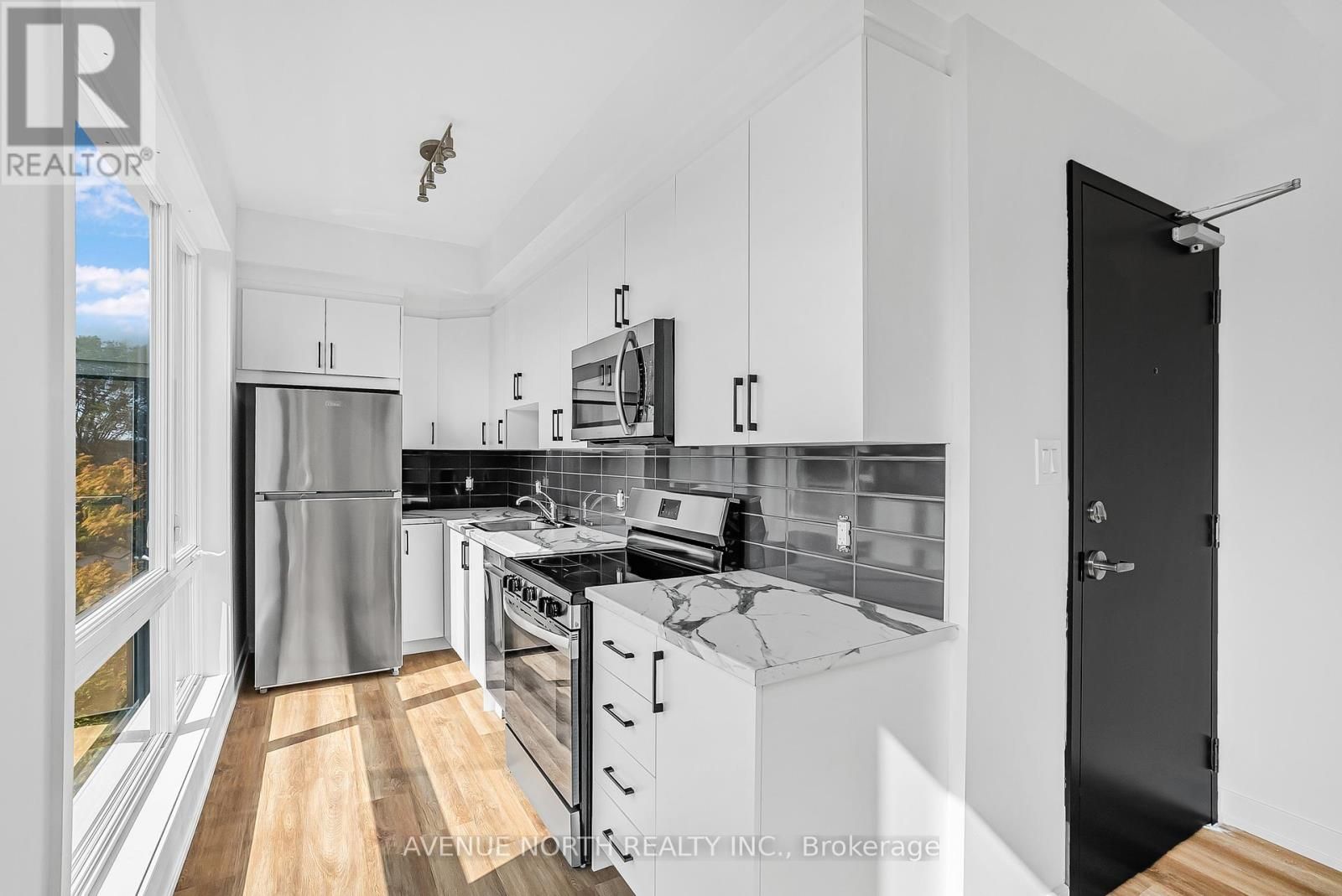 A kitchen with stainless steel appliances and white cabinets.