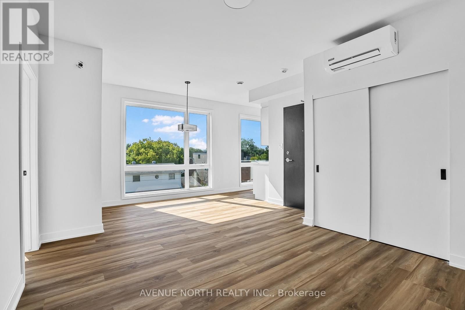 A large empty room with hardwood floors and white walls.