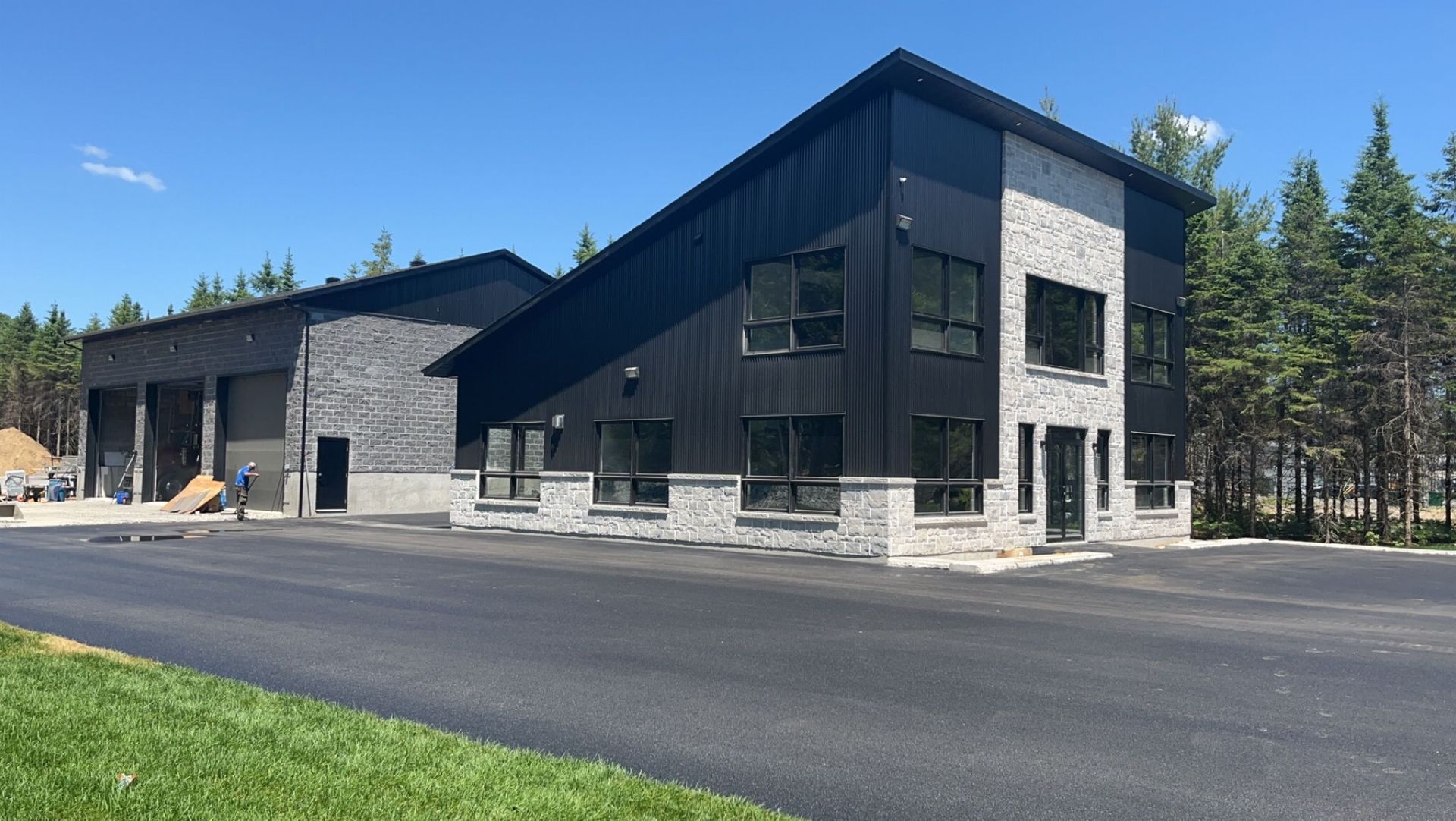 A large black building with a lot of windows is sitting next to a road.