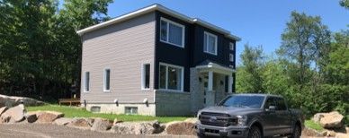 A gray truck is parked in front of a small house.
