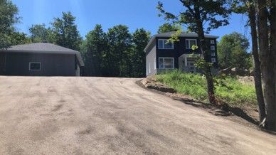 A house is sitting on top of a hill next to a dirt road.