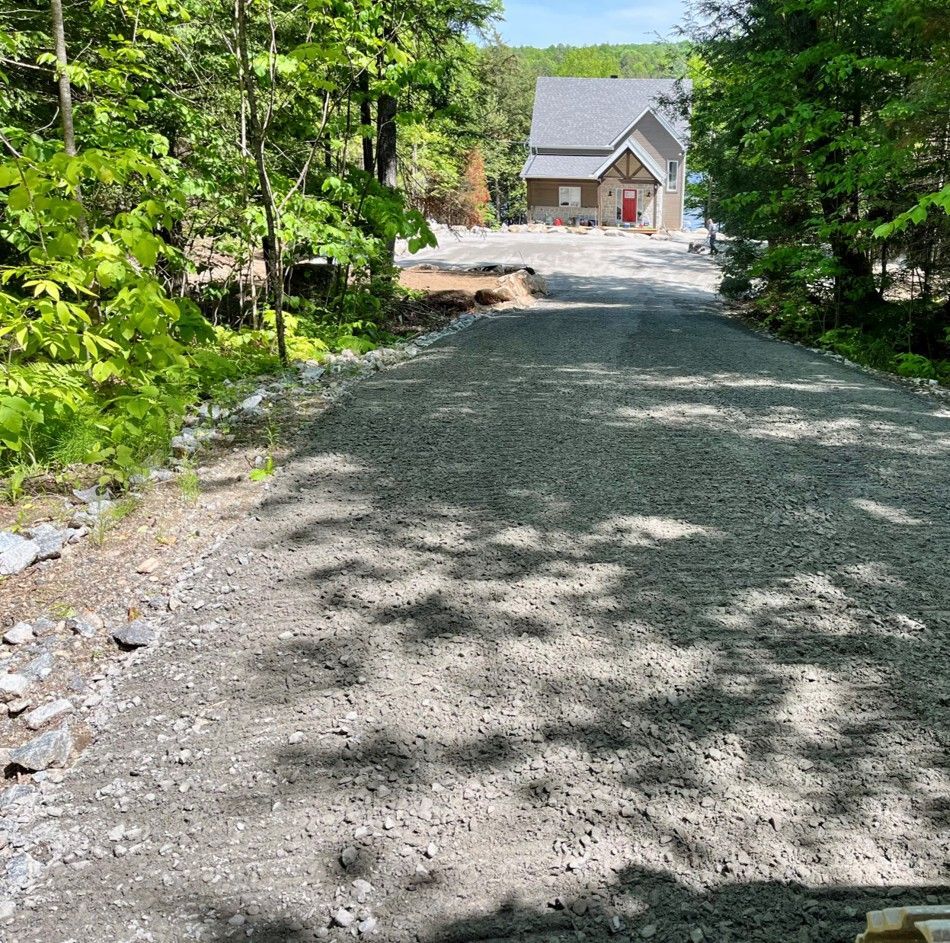 A gravel road leading to a house surrounded by trees