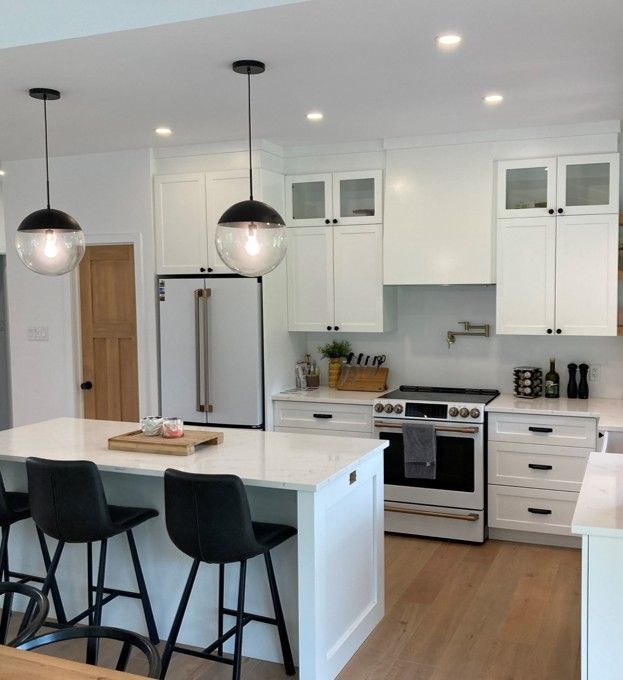 A kitchen with white cabinets and black stools