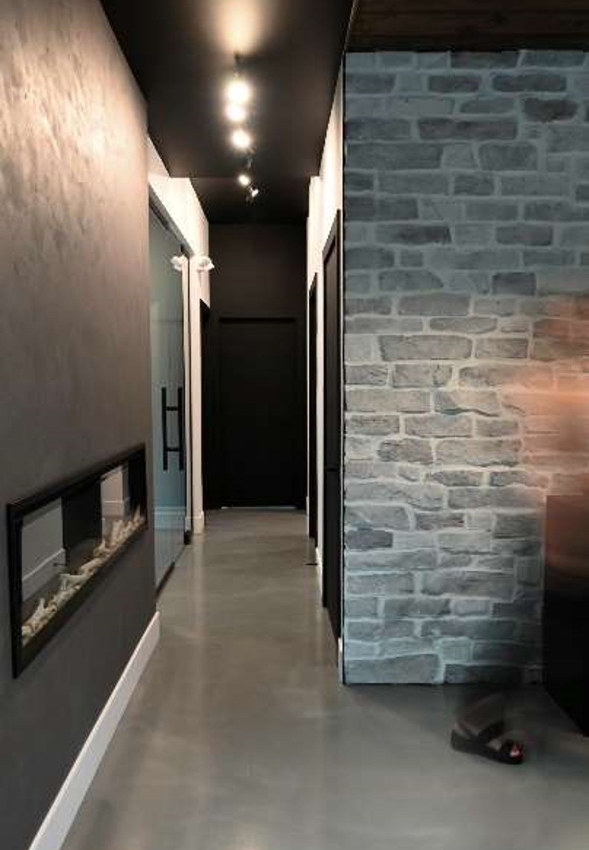 A long hallway with a brick wall and a fireplace.