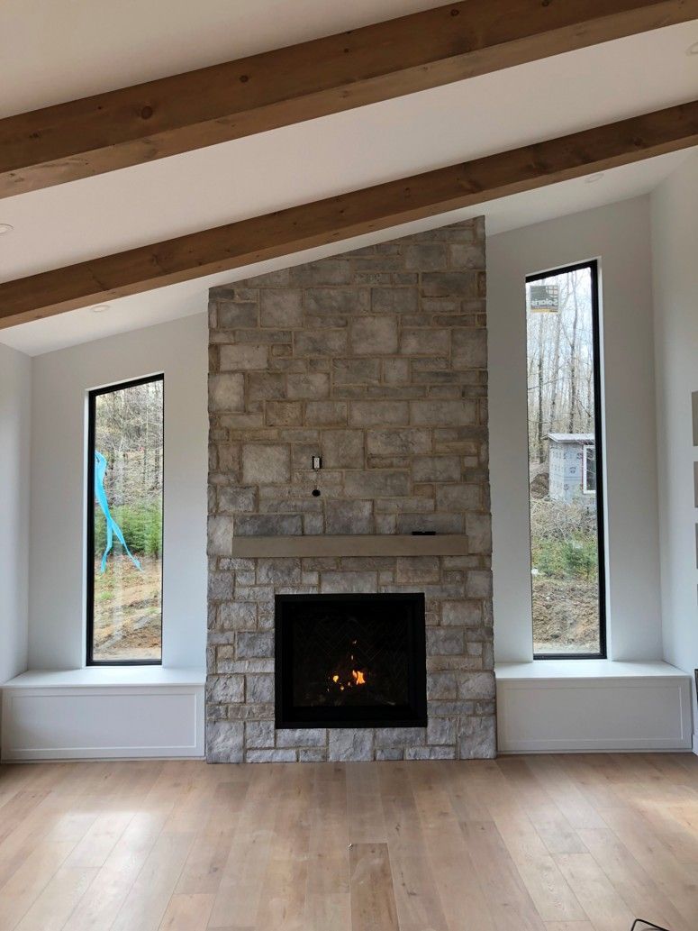 A living room with a brick fireplace and two windows.