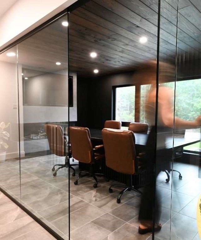 A conference room with a glass wall and a table and chairs