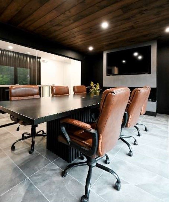 A conference room with a table and chairs and a flat screen tv on the wall.