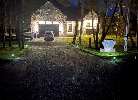 A gravel driveway leading to a house at night