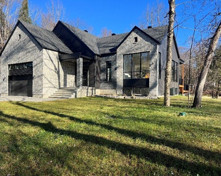 A large house with a lot of windows is sitting in the middle of a lush green field.