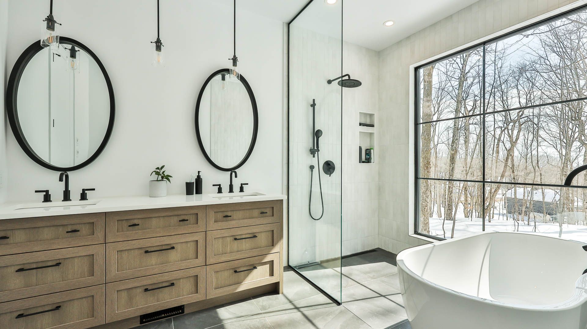 A bathroom with two sinks , a tub , a shower and a large window.
