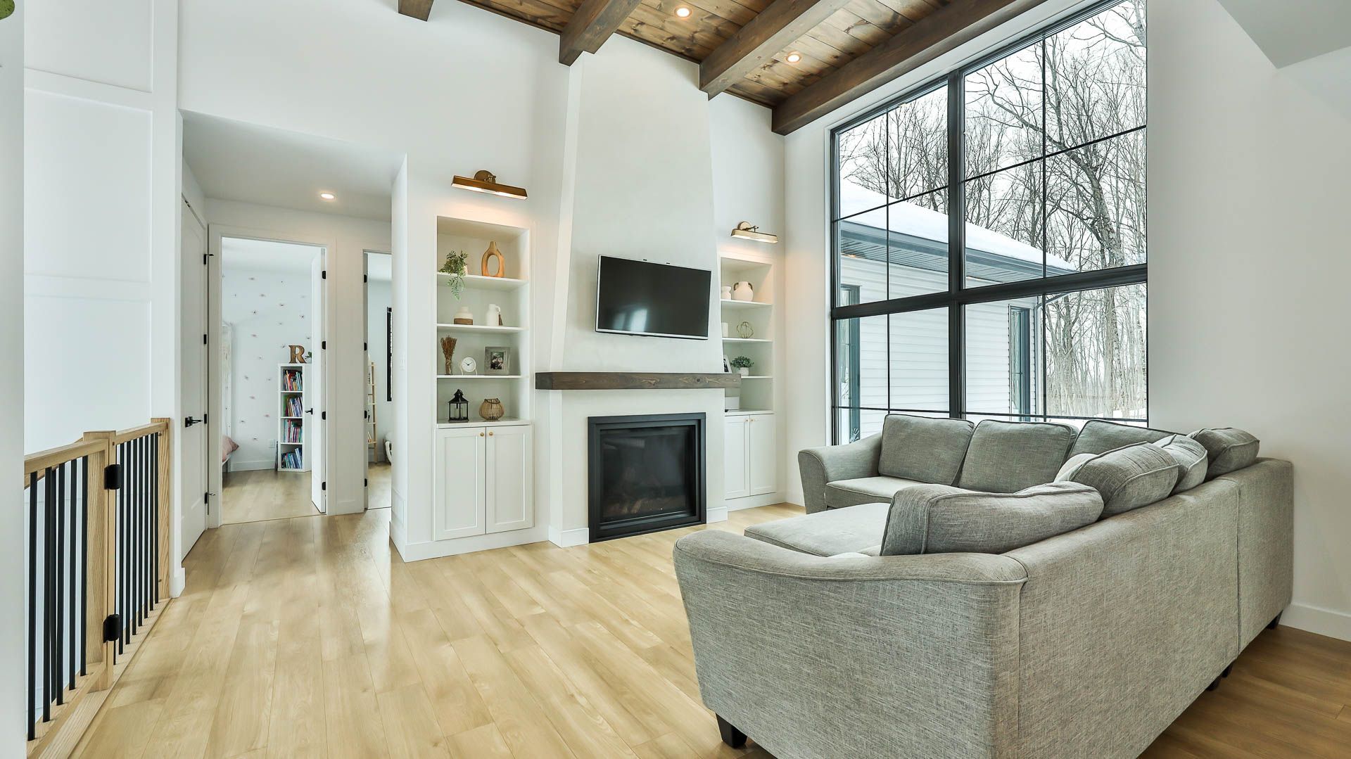 A living room with a couch , fireplace , television and large windows.