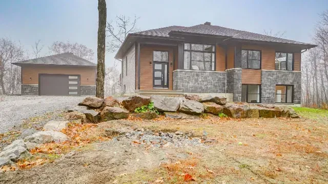 Une grande maison est située au sommet d'une colline au milieu d'une forêt.