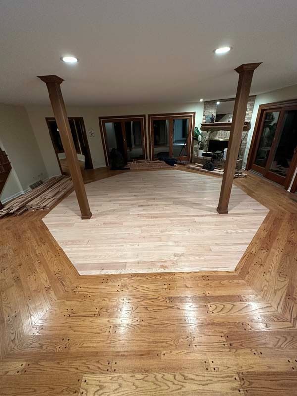 Indoor room with hardwood floor, central octagonal light wood platform, and four support posts under ceiling lights