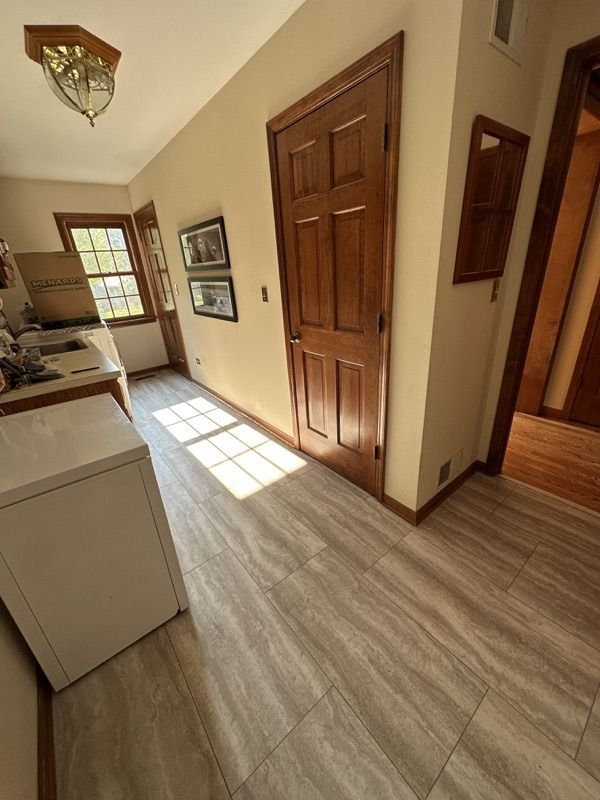 Narrow hallway with wood doors, light laminate flooring, and sunlight streaming through a window.